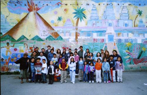 [Filipino Education Center Galing Bata staff, parents, and students in the school yard by the mural]