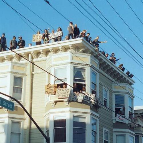 [People holding signs on roof and windows of apartment in support of Pink Saturday Dyke March in 2007 at 18th and Guerrero Streets]