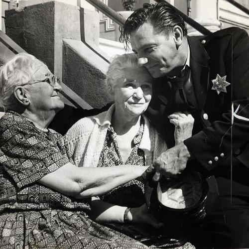 [Officer Clayton Matthews comforting Mrs. Cecil Thomas (left) and Mrs. Mary E. Sowden (center) after rescuing them from a fire]