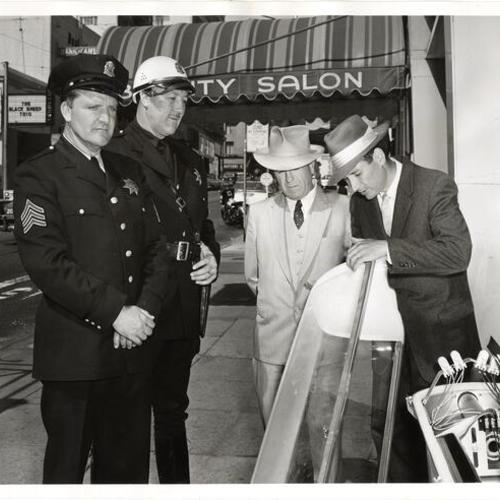 [D. Aboudara from General Electric Company explains the construction of the newly designed plastic globe. Police Sergeants V. Desmond and R.C. Gremminger look on.]