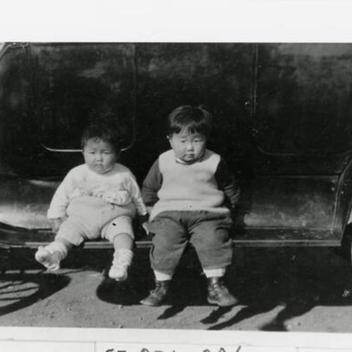 [Children sitting on running board of a car in the 1920's]