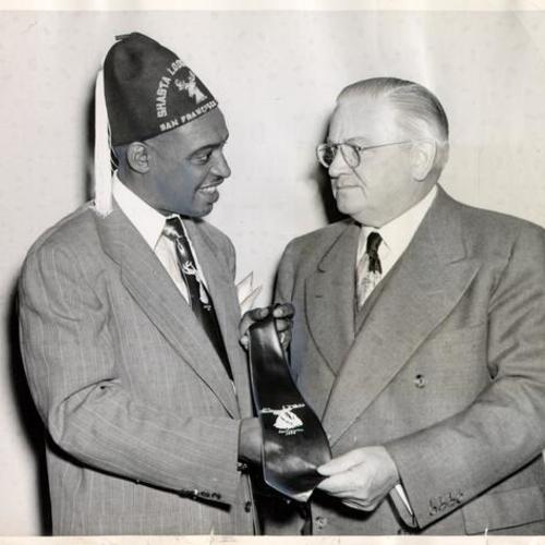 [Musician Lionel Hampton presenting a gift tie to Mayor Elmer E. Robinson]
