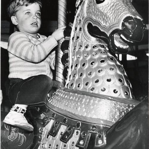 [Kid riding merry-go-round in Children's Playground, Golden Gate Park]
