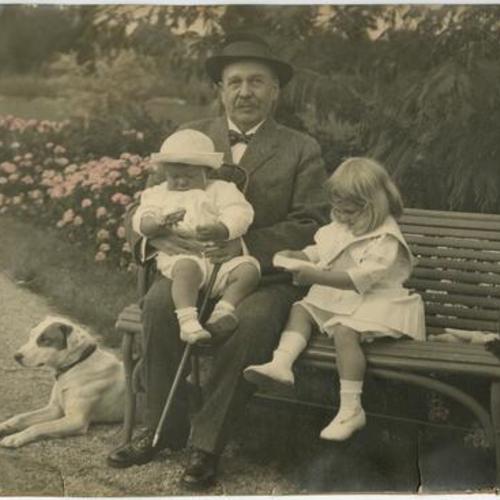 [Adolph Bernard Spreckels, Sr. holding Adolph Bernard Spreckels, Jr. sittin on bench and next to Alma Emma Spreckels]