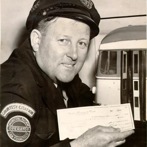 [Muni bus driver Eugene McIsaacs displaying a check he received as part of a "Muni Man of the Month" award]