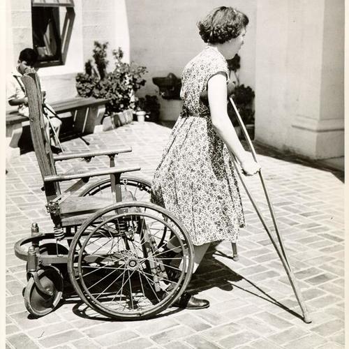 [Girl walking with crutches in a courtyard at Sunshine Orthopedic School]