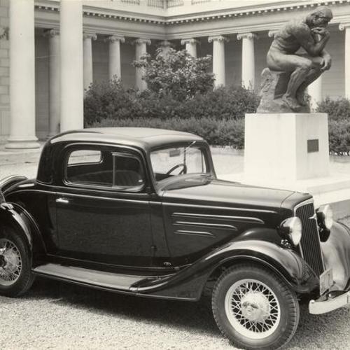 [Two women standing next to an automobile parked in the courtyard at the Palace of the Legion of Honor]