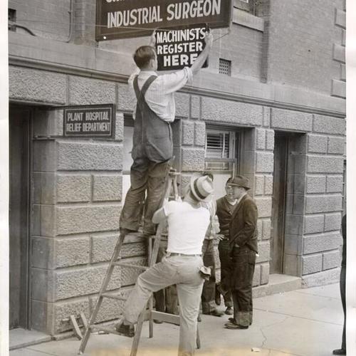 [W. D. Wightman putting up a sign calling for machinists to register for work at the Bethlehem Shipbuilding Corporation plant in San Francisco]
