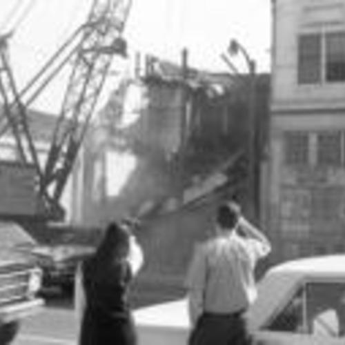 [Two people watch from across the street as building is demolished, part of South of Market Redevelopment, 