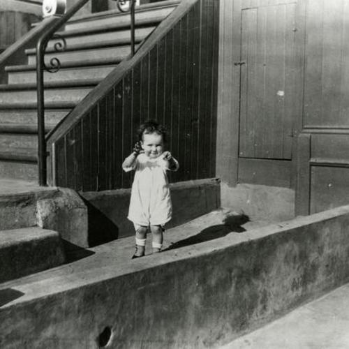 [Portrait of child in front of house on Treat Street]