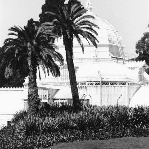 [Two people sitting on a bench outside the Conservatory of Flowers in Golden Gate Park]