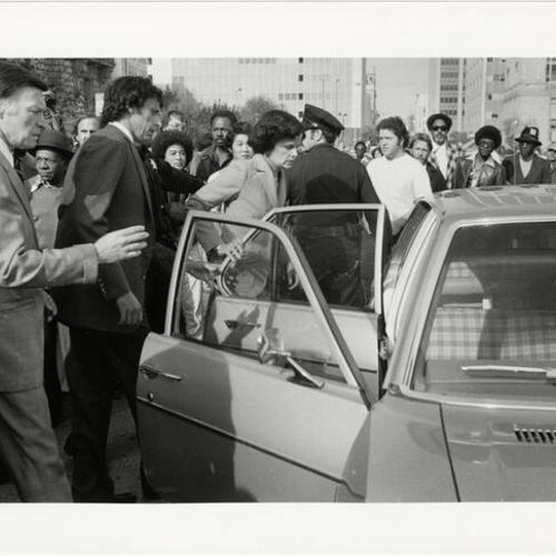 [Police Chief Charles Gain, Richard Blum and Dianne Feinstein entering police vehicle following the murders of George Moscone and Harvey Milk]