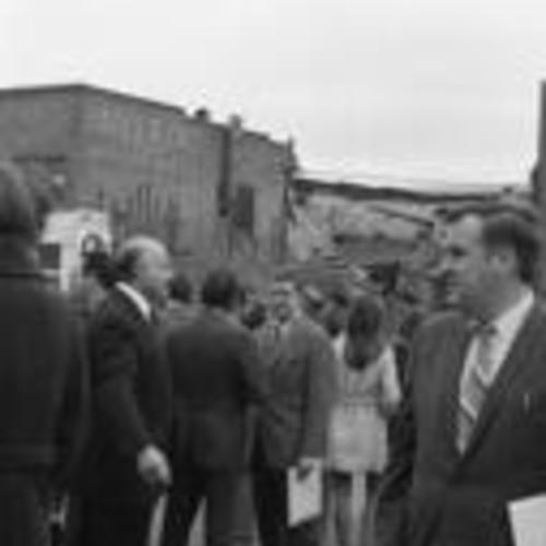 [Mayor Joseph Alioto (left of center) and others, demolished building in background,
