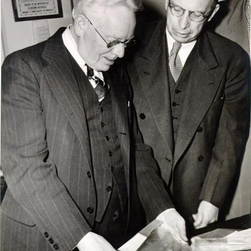 [Alcatraz Prison warden James A. Johnston and James V. Bennett, director of the Federal Bureau of Prisons, examining the implement used by Alcatraz convict Paul Bernard Coy to pry bars open in a failed escape attempt]