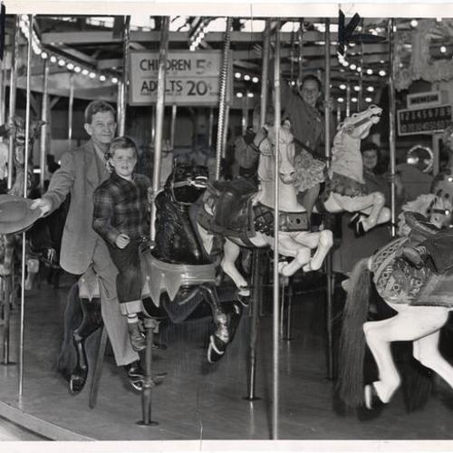 [Charles Coryell and a friend riding the Merry-Go-Round at Playland at the Beach]