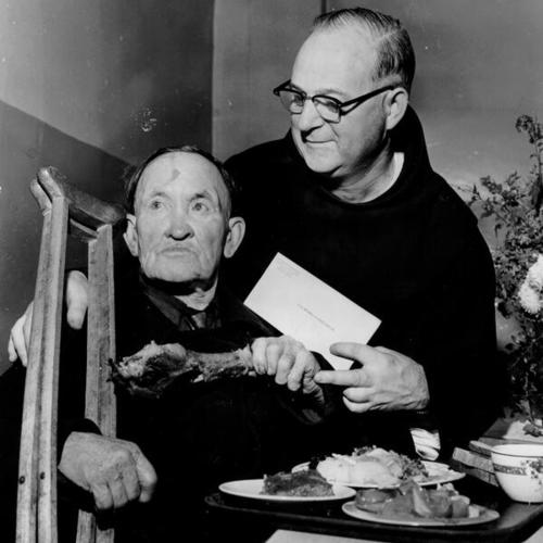 [Father Alfred Boeddeker watches as Walter McDonald, age 67, eats turkey at St. Anthony's]