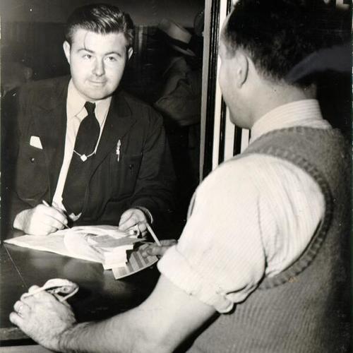 [Municipal bus driver William J. Donahue checking out tokens, transfers and operating forms from a clerk at a Muni bus barn]