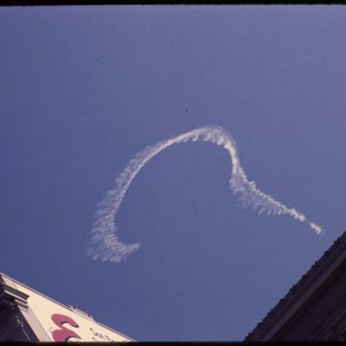 View of contrails in sky above San Francisco buildings