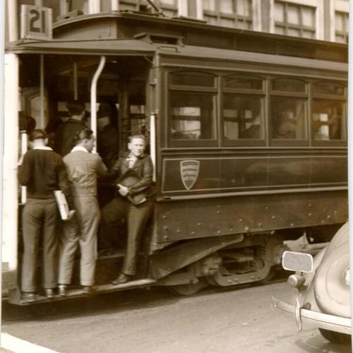 [Schoolboys riding on the steps of a streetcar]
