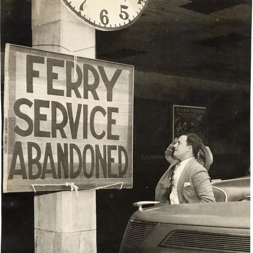 [George Aronov of San Francisco reading "Ferry Service Abandoned" sign]