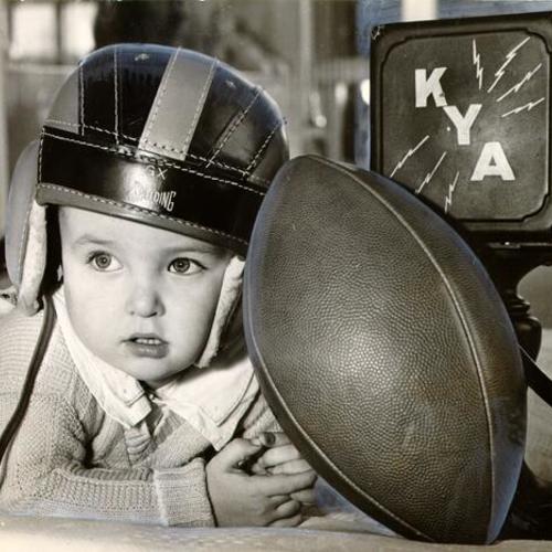 [Child from Shriners' Hospital for Crippled Children posing with a football]