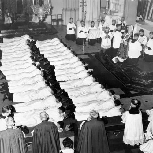 [Thirty-three new priests lying face down before Archbishop John J. Mitty in Old St. Mary's Cathedral]