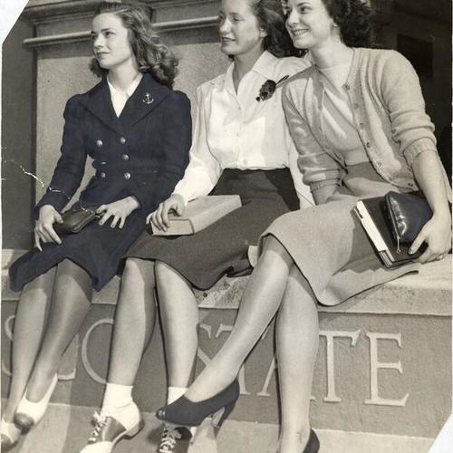 [Three female students sitting at the entrance to San Francisco State College]