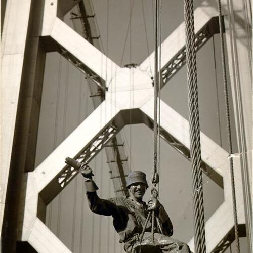 [Bridge worker hanging by rope on the San Francisco-Oakland Bay Bridge]