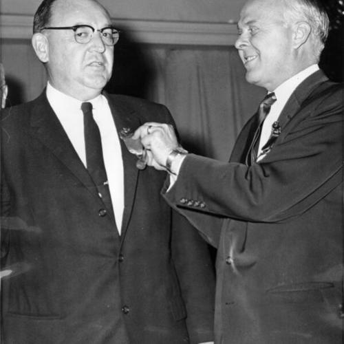 [Governor-elect Edmund G. (Pat) Brown receives delegate badge from Tommy Pitts, President of the new California Labor Federation AFL-CIO]