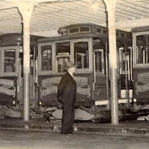[Superintendent J. J. deMoor inspecting cable cars inside the cable car barn at California and Hyde streets]