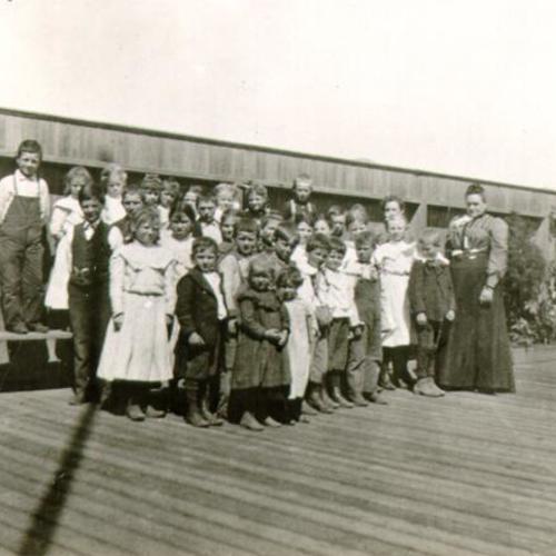 [Group of children and an adult posing for a picture in Visitacion Valley]