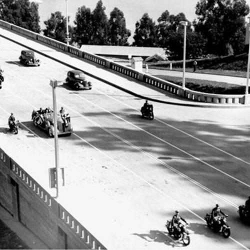 [Official vehicles accompanied by motorcycle escort approaching the East Portal of the Yerba Buena tunnel on opening day of San Francisco-Oakland Bay Bridge]