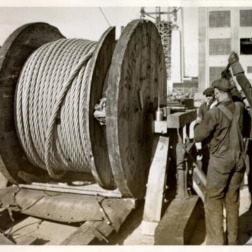 [Construction workers preparing to string the first cable on the San Francisco-Oakland Bay Bridge]