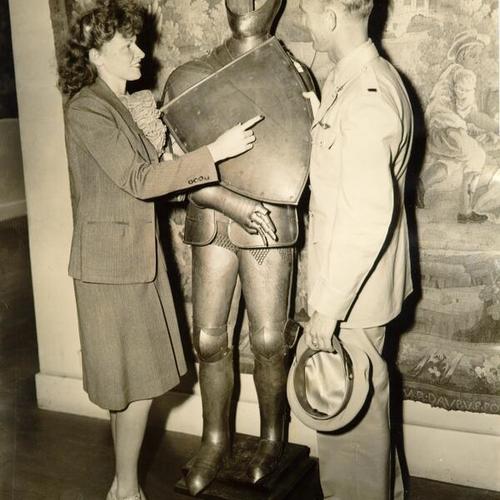 [Two unidentified people look at a suit of armor during an auction at the De Young Museum in Golden Gate Park]