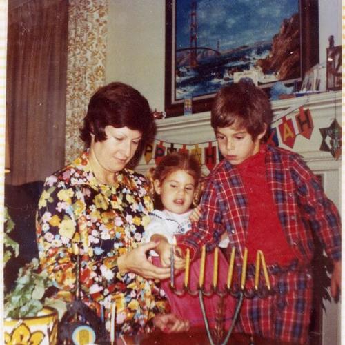 [Heddy lighting candles during Hanukkah with her children Sylvia and David]