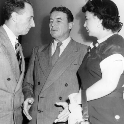 [Attorney Vincent Hallinan, center, chats with Harry Bridges and Mrs. Bridges after the initial day of a hearing on the Government motion to revoke bail and jail Bridges]