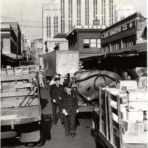 [Two policemen issuing tickets to produce delivery trucks on Washington Street]