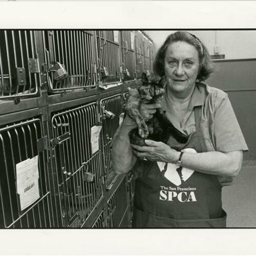 [Volunteer holding cat by kennels in SF/SPCA]