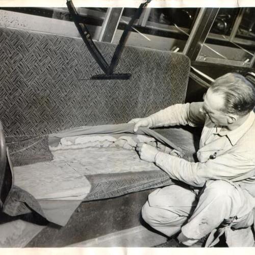 [Municipal Railway employee Charles McGuire inspecting damaged seats on a Muni bus]