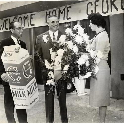 [George Christopher being greeted by his sister, Helen, and brother in law Mickey Davies, president of a dairy firm]