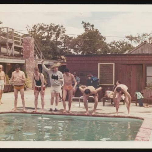 People preparing to dive into swimming pool