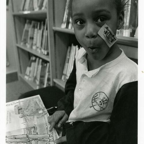 A young child reads a picture story in the Fisher Children's Center of the San Francisco Public Library on opening day