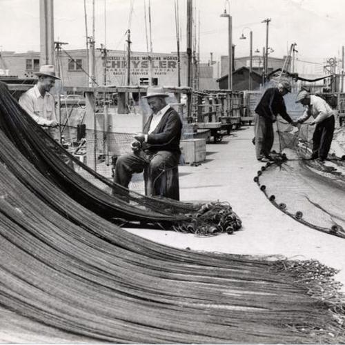 [Joe Crivello and Nino Alioto repairing fishing nets at Fisherman's Wharf]