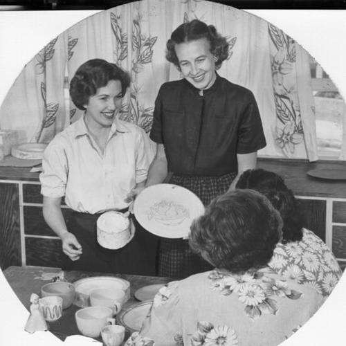 [Mrs. Morton B. Jackson (left) and Mrs. Carl F. Belliston showing examples of their craftmaking to Florence Crittenton residents]