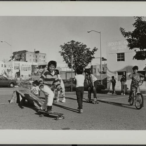 Children biking and skateboarding in parking lot in South of Market