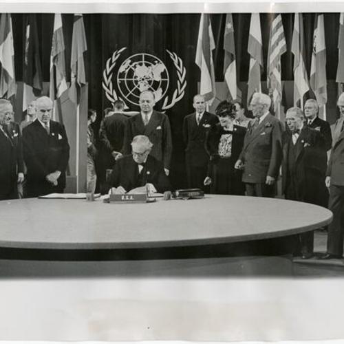 [President Truman and American delegation watching Senator Tom Connally sign the United Nations Charter]
