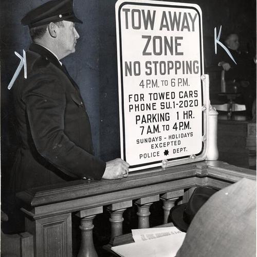 [Police officer George Langley displaying new traffic towaway warning sign]
