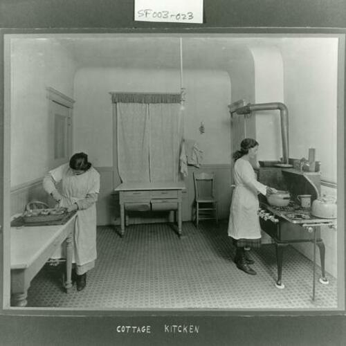 [Two girls cooking in the kitchen at Homewood Terrace Orphanage]