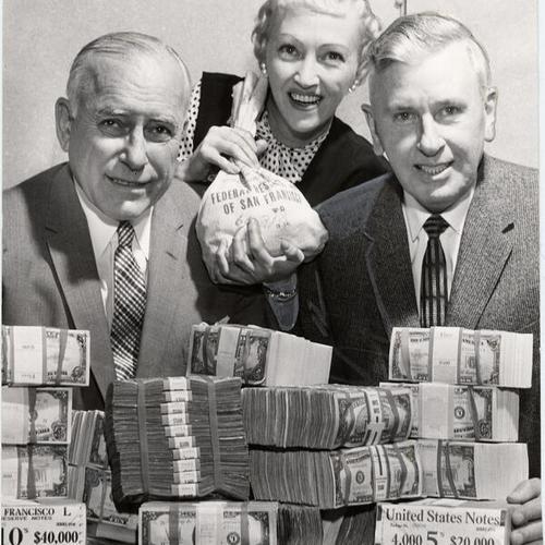 [Roy N. Buell, Marguerite Cook and James W. Reinfeld posing with $2,000,000 in cash]