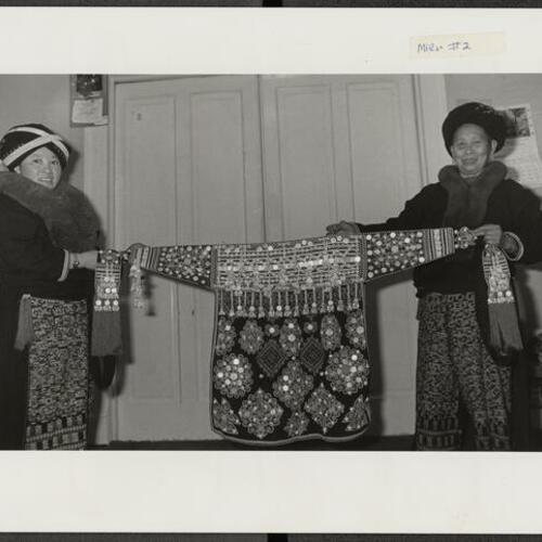Mien women holding traditional Mien garment for annual craft fair at Women's Building
